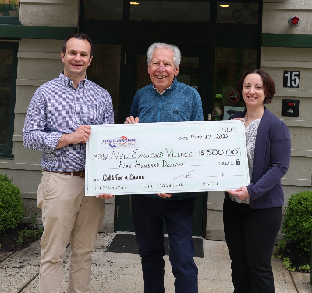 Cotti Johnson representatives presenting a $500 check to New England Village, supporting individuals with disabilities through the 'Cotti for a Cause' initiative.