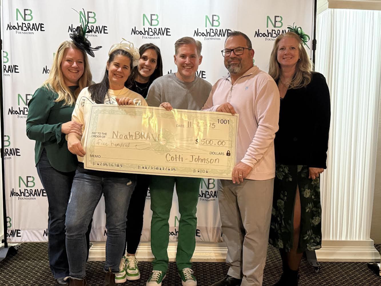 Cotti-Johnson HVAC representatives presenting a $500 donation check to the NoahBRAVE Foundation, surrounded by supporters, at a community event.